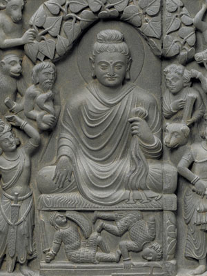 Detail of stone relief of seated Gautama Buddha, surrounded by mountain men, animals, and devas.